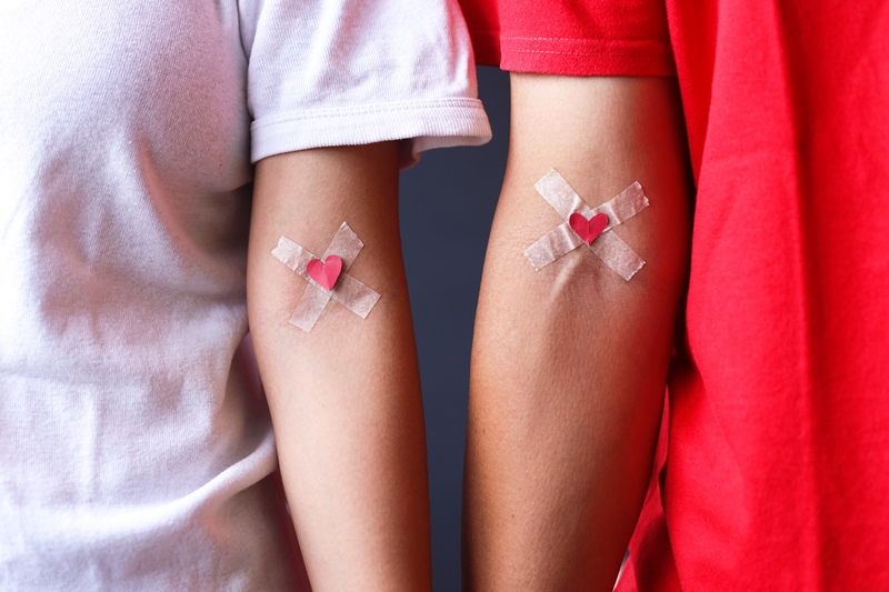 Man in red and woman in white T-shirt with hands taped patch after giving blood with red heart. Blood donation concept and Blood donorship. centro donazione sangue Palermo